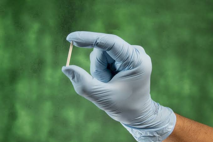 Implante hormonal segurado por mão com luva cirúrgica